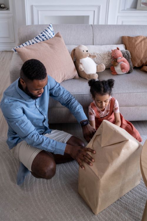 Free Father and daughter bonding as they unwrap a present together in a cozy living room. Stock Photo