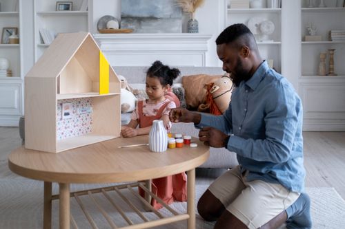 Free Father and daughter enjoy bonding while painting in a cozy living room setting. Stock Photo