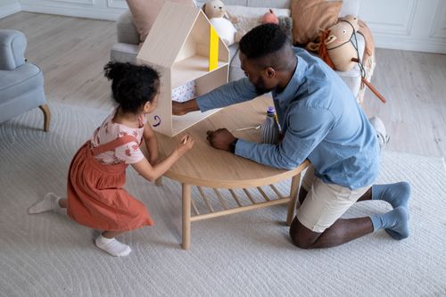 Free A father and daughter share quality time bonding over a creative dollhouse project at home. Stock Photo