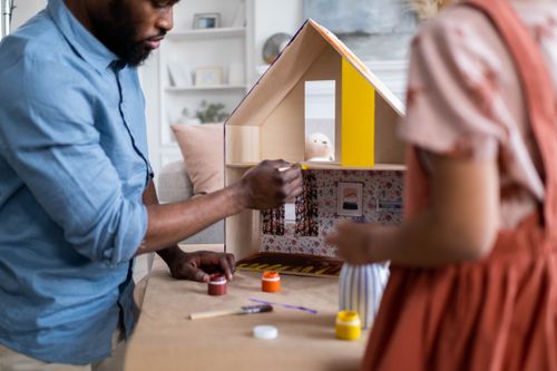 Free A man and a child painting a dollhouse together, focusing on creativity and craftsmanship. Stock Photo