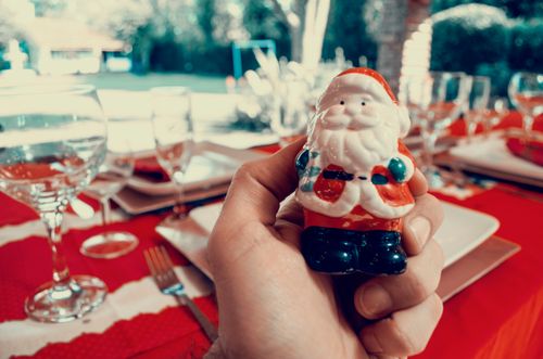 Free Hand holding Santa figurine at a festive table setting with glassware and cutlery. Stock Photo