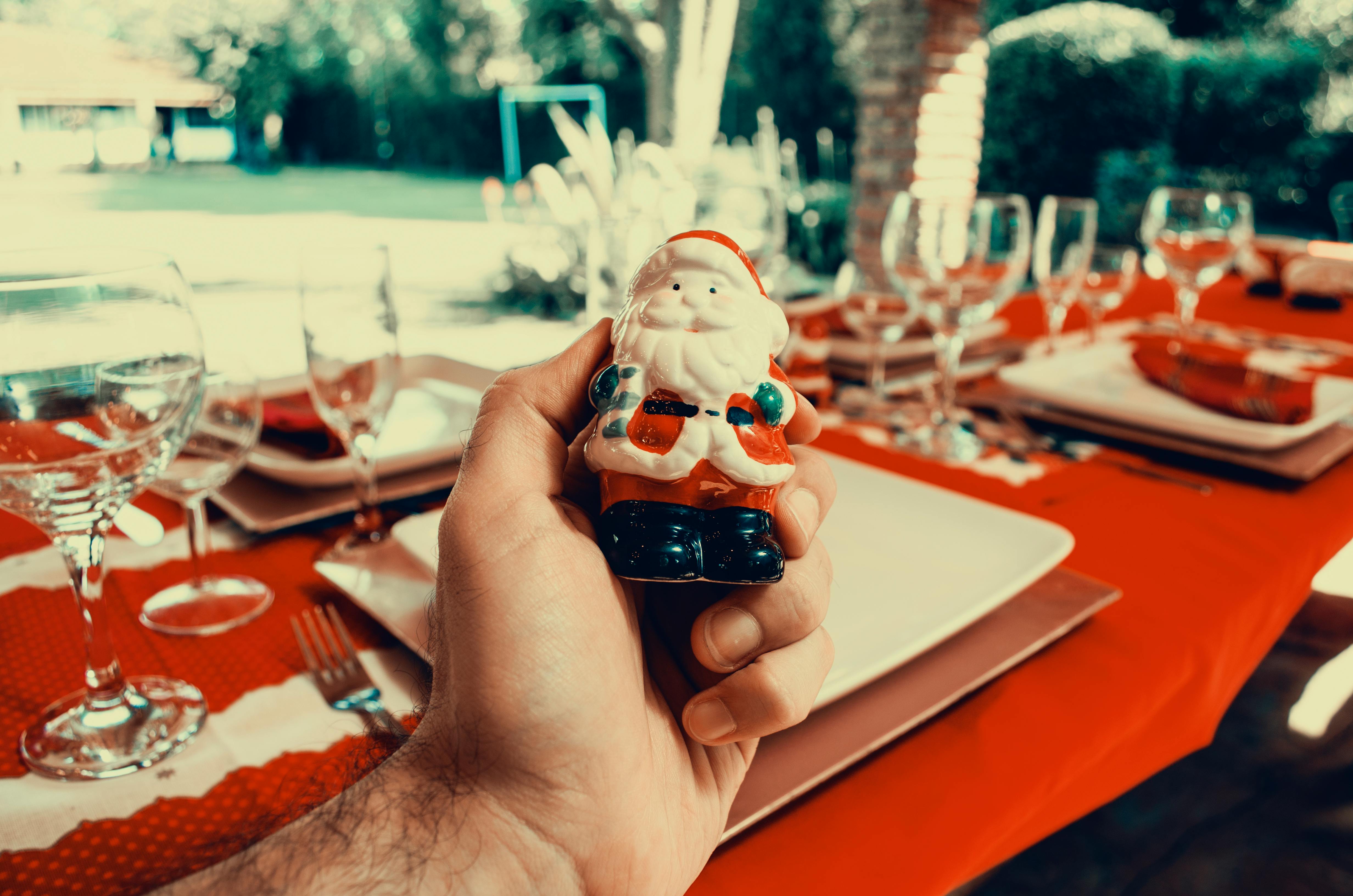 手持圣诞老人雕像参加户外节日餐桌活动，非常适合庆祝圣诞节