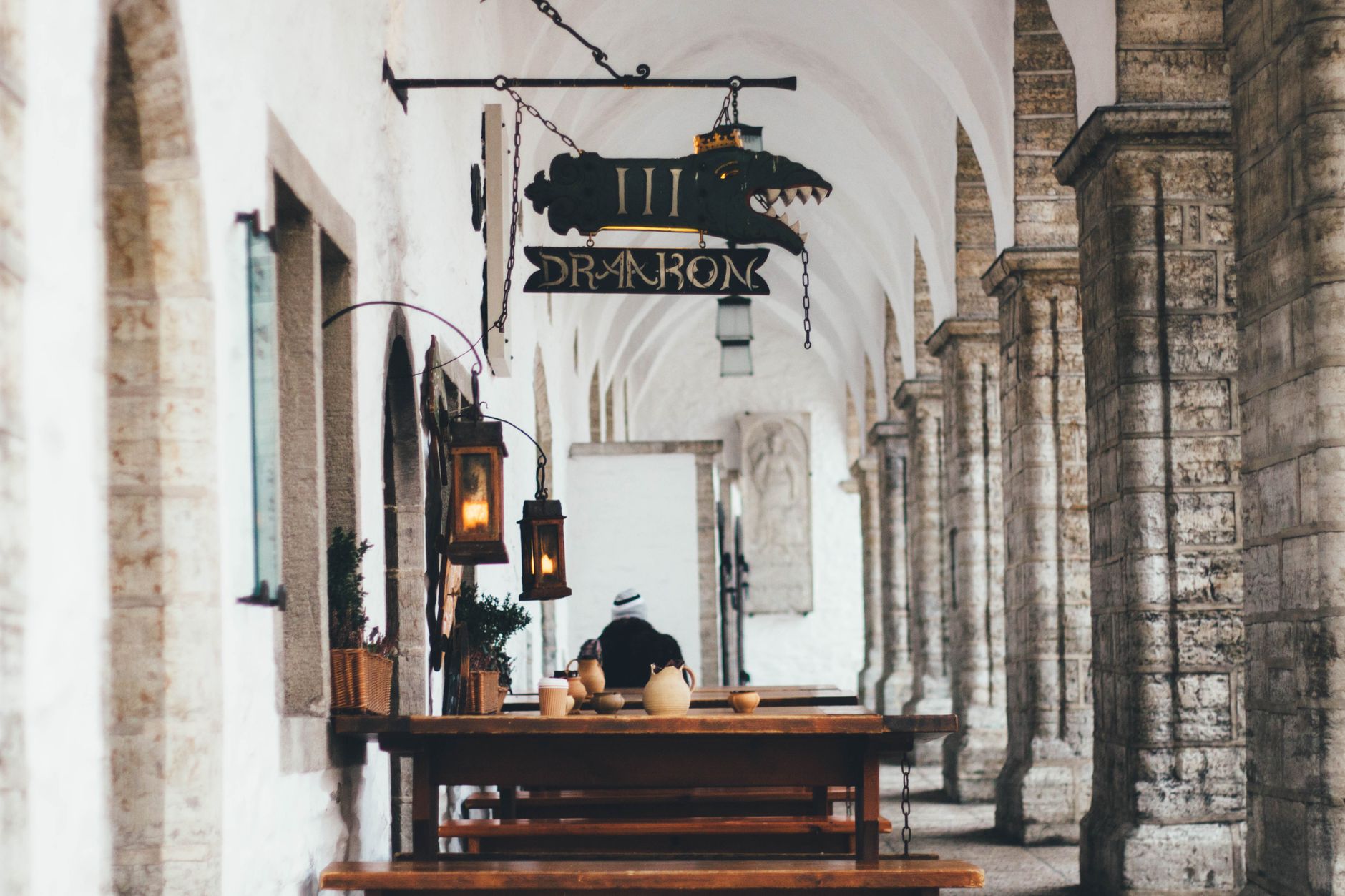 Charming medieval style archway with rustic dining tables and intricate signage.