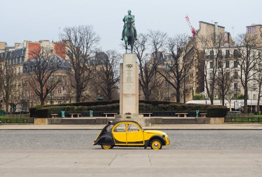 Classic yellow Citroën 2CV in front of the Foch Monument in Paris, capturing a vintage charm.