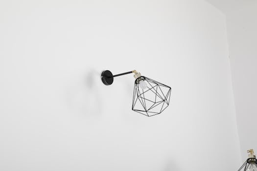 A minimalist wall lamp with a geometric design against a white wall, perfect for modern decor.