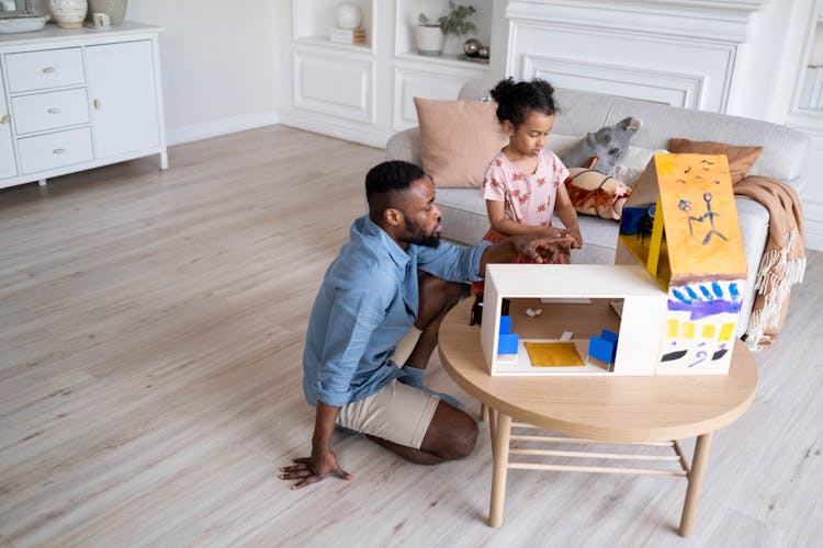 Father And Daughter Playing With A Dollhouse