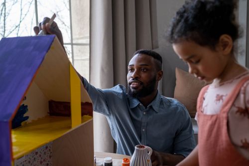 Free A father and daughter enjoying creative time painting together indoors. Stock Photo