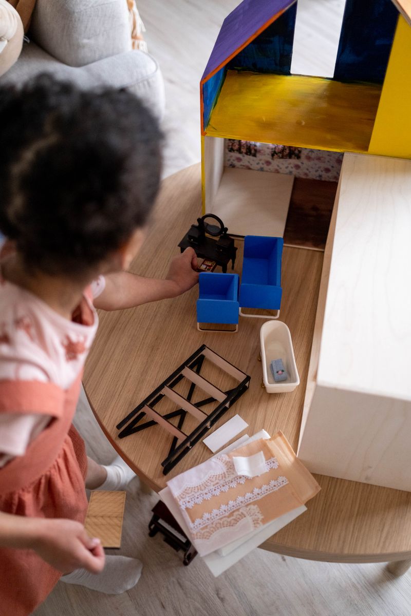 Petite fille jouant avec sa maison de poupée en bois de manière créative
