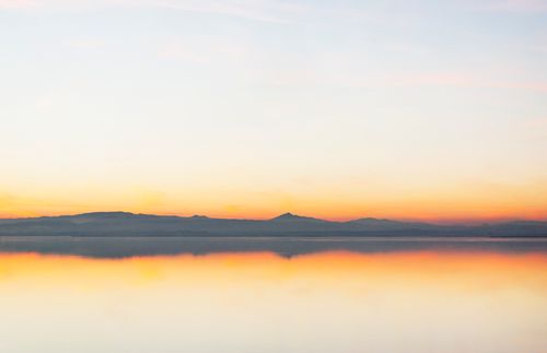 Free Tranquil lake reflection of mountains under a colorful sunset sky. Stock Photo