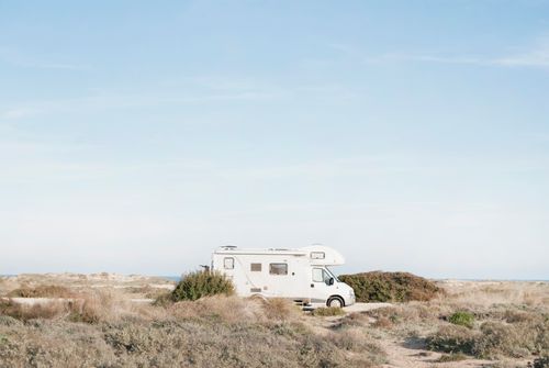 Free A serene view of an RV parked in a dry landscape, under a clear blue sky. Stock Photo