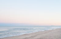 黎明时分，平静的海岸景色，海浪温和，天空柔和，营造出宁静