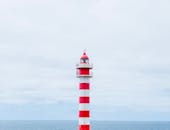 在西班牙拉斯帕尔马斯，一座引人注目的红白灯塔耸立在多云的天空中