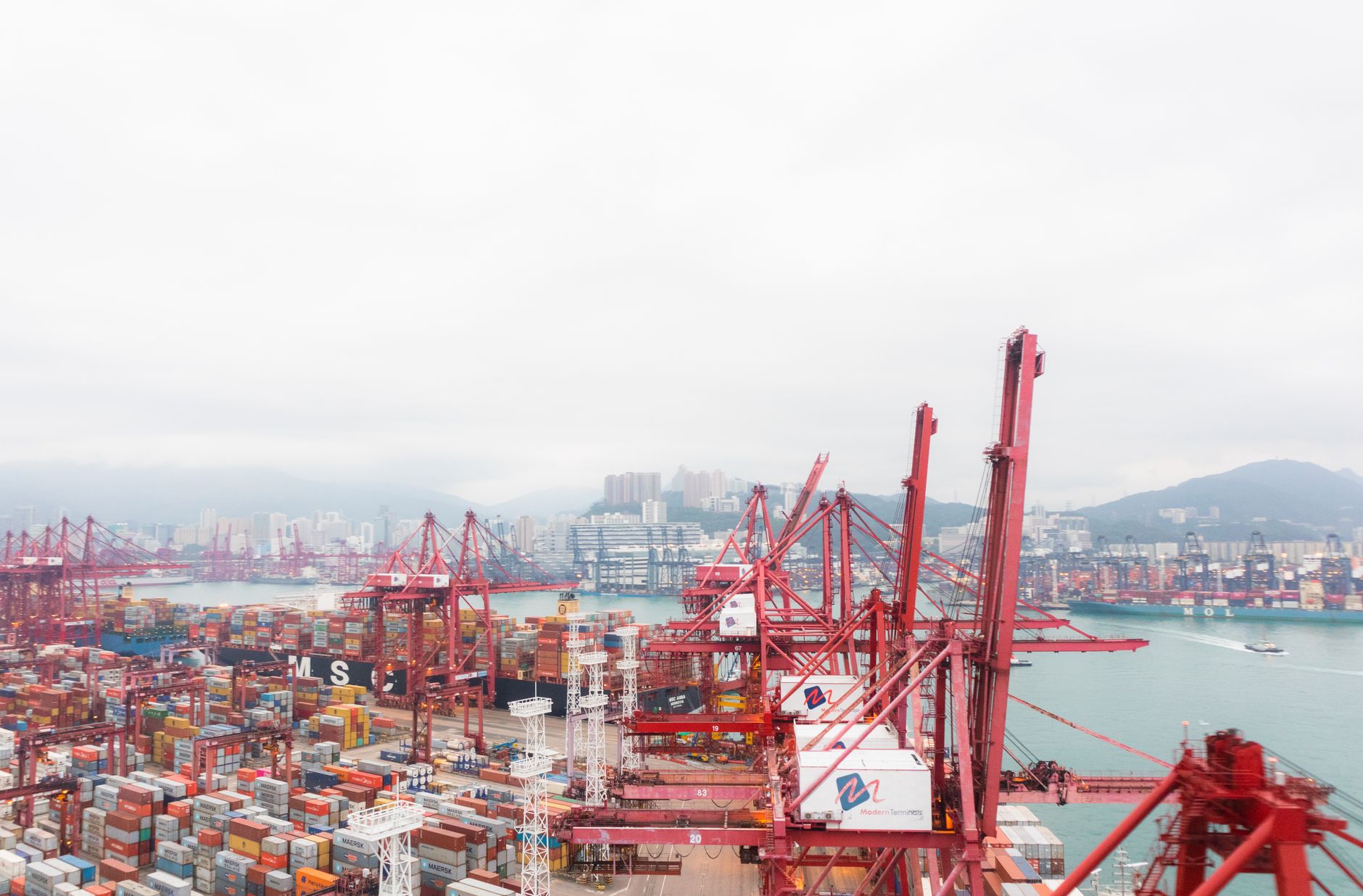 A vibrant harbor view showcasing cranes and shipping containers at a busy port.