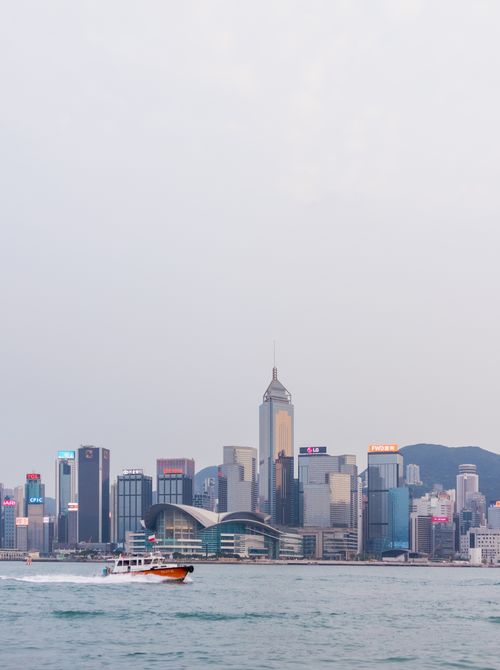 Free Stunning view of Hong Kong's urban skyline over Victoria Harbour with a boat in the foreground. Stock Photo