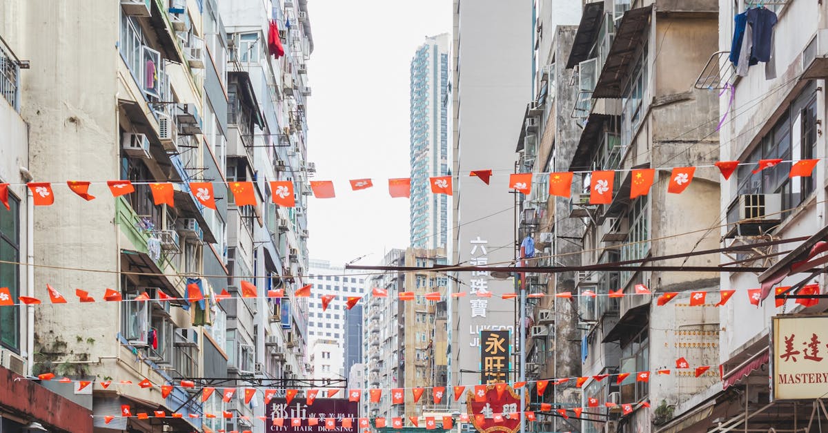 Photo by Ana Benet Vibrant street view of Hong Kong with colorful flags, buildings, and people walking.