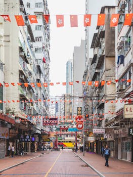 Photo by Ana Benet Vibrant street view of Hong Kong with colorful flags, buildings, and people walking.