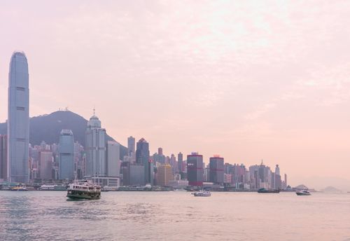 Free Serene view of the Hong Kong skyline at sunset with boats on Victoria Harbour. Stock Photo
