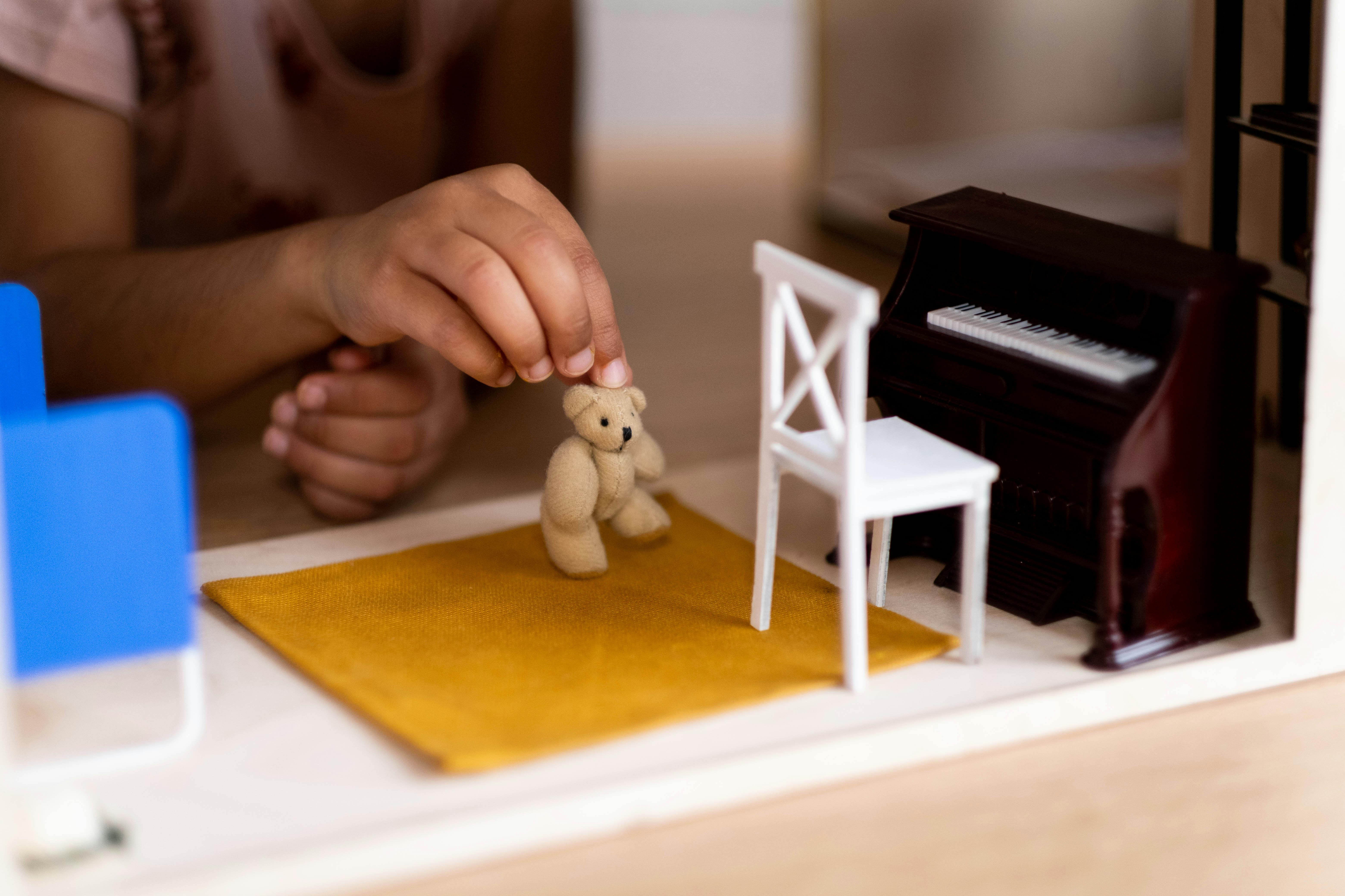 child playing with miniature toys in a dollhouse