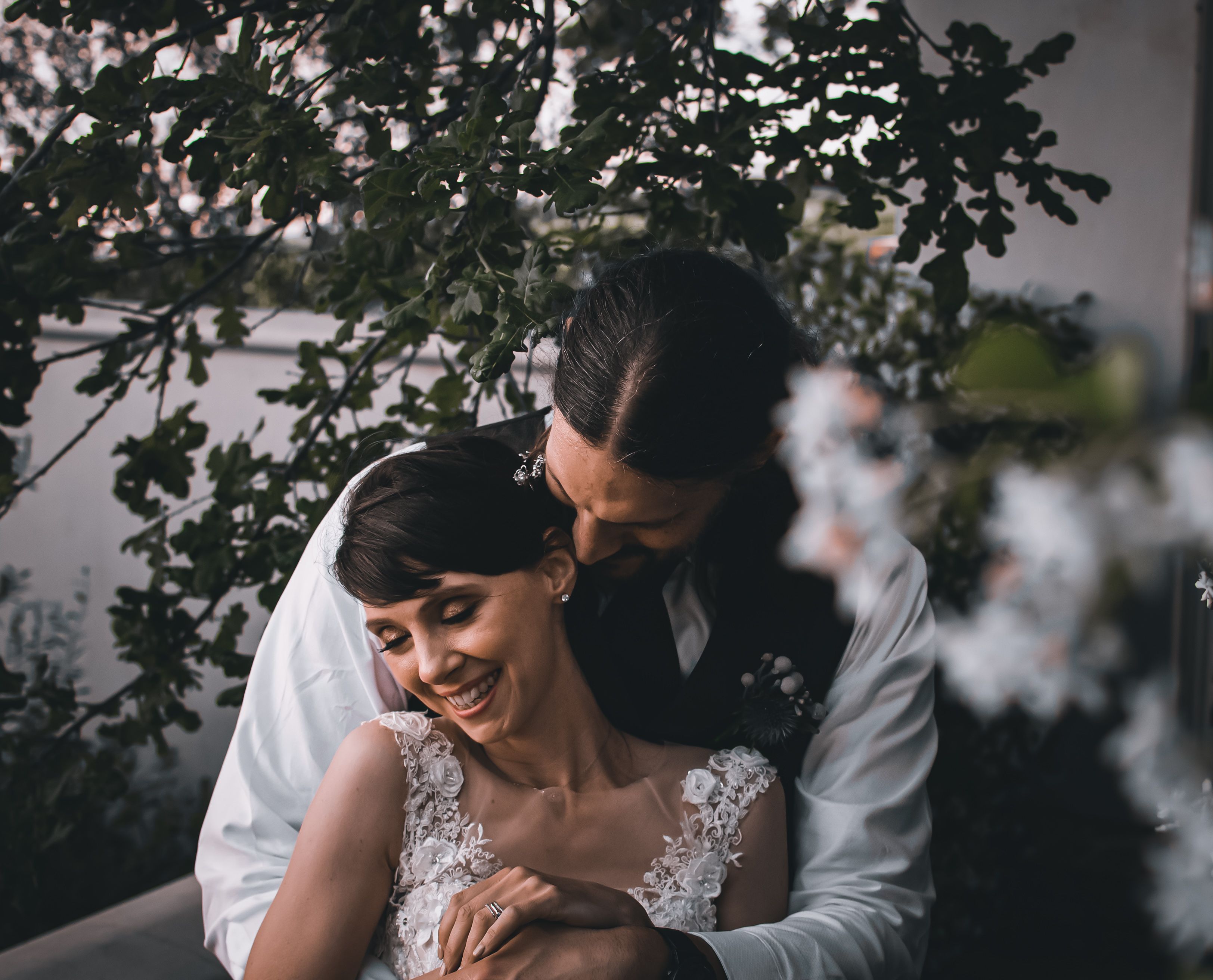 A joyful bride and groom sharing a loving embrace under trees. Perfect wedding day moment.