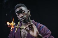 An African American man engaged in a ritual involving fire and symbolizing dark magic.