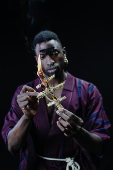 A Man in Maroon Robe Holding a Burning Stick