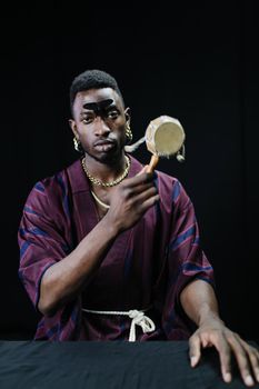 A Man in Maroon Robe Holding an Object