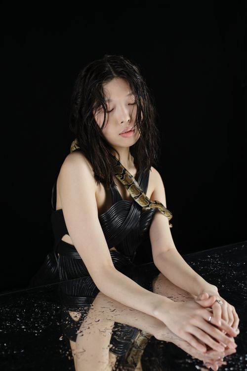Free Studio portrait of a woman with a snake draped over her shoulders, reflected on a black surface. Stock Photo