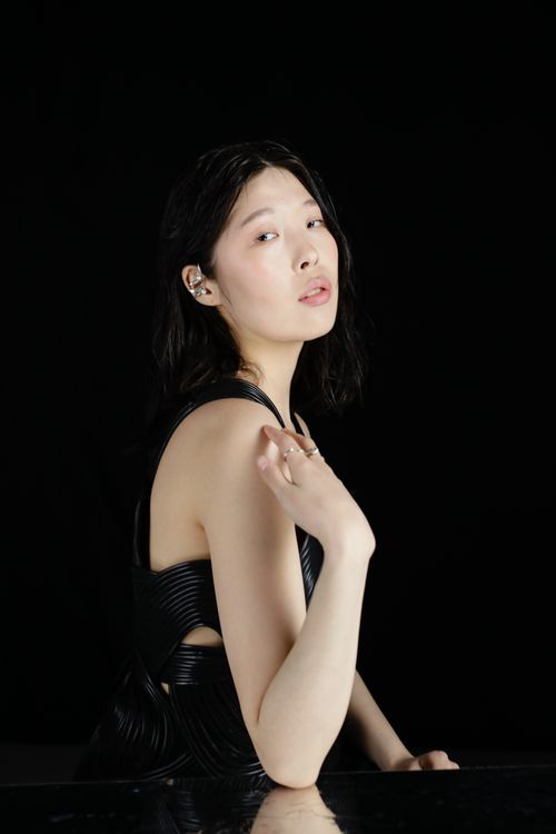 Free Studio portrait of a fashionable woman posing in black attire against a dark background. Stock Photo