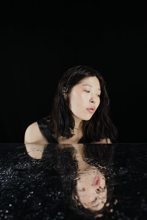 Free Captivating portrait of an Asian woman with mirror reflection on black background. Stock Photo