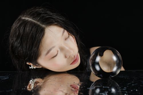 Free Close-up of a woman with a crystal ball reflected in water, creating a mysterious atmosphere. Stock Photo