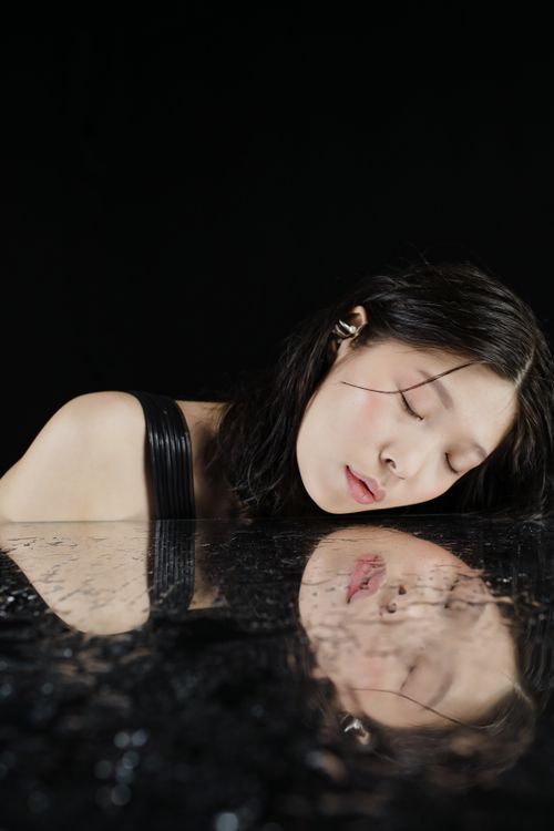 Free An Asian woman rests her head with eyes closed, reflecting peacefully. Stock Photo