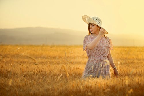 Woman in Off Shoulder Floral Dress Standing on Brown Grass Field