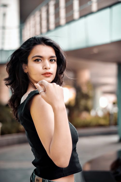 Free Portrait of a fashionable young woman posing confidently in an urban environment, exuding style and grace. Stock Photo