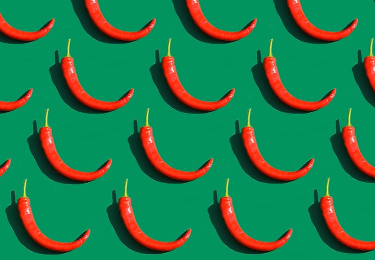 Chili Peppers In Rows On Green Background 