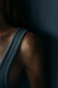 Intimate and moody close-up of a woman's shoulder in a sports bra, highlighting fitness.