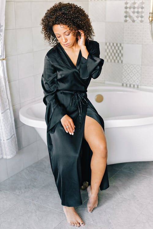 Woman in Black Silk Robe sitting on a Bathtub 