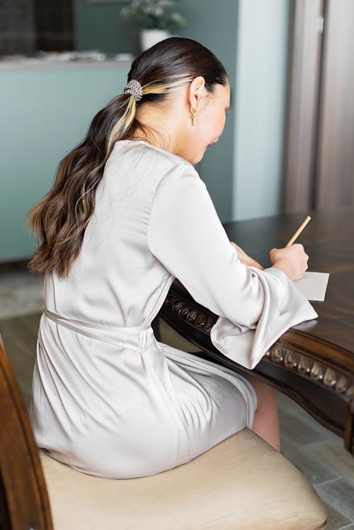 A Woman Sitting While Writing on the Paper