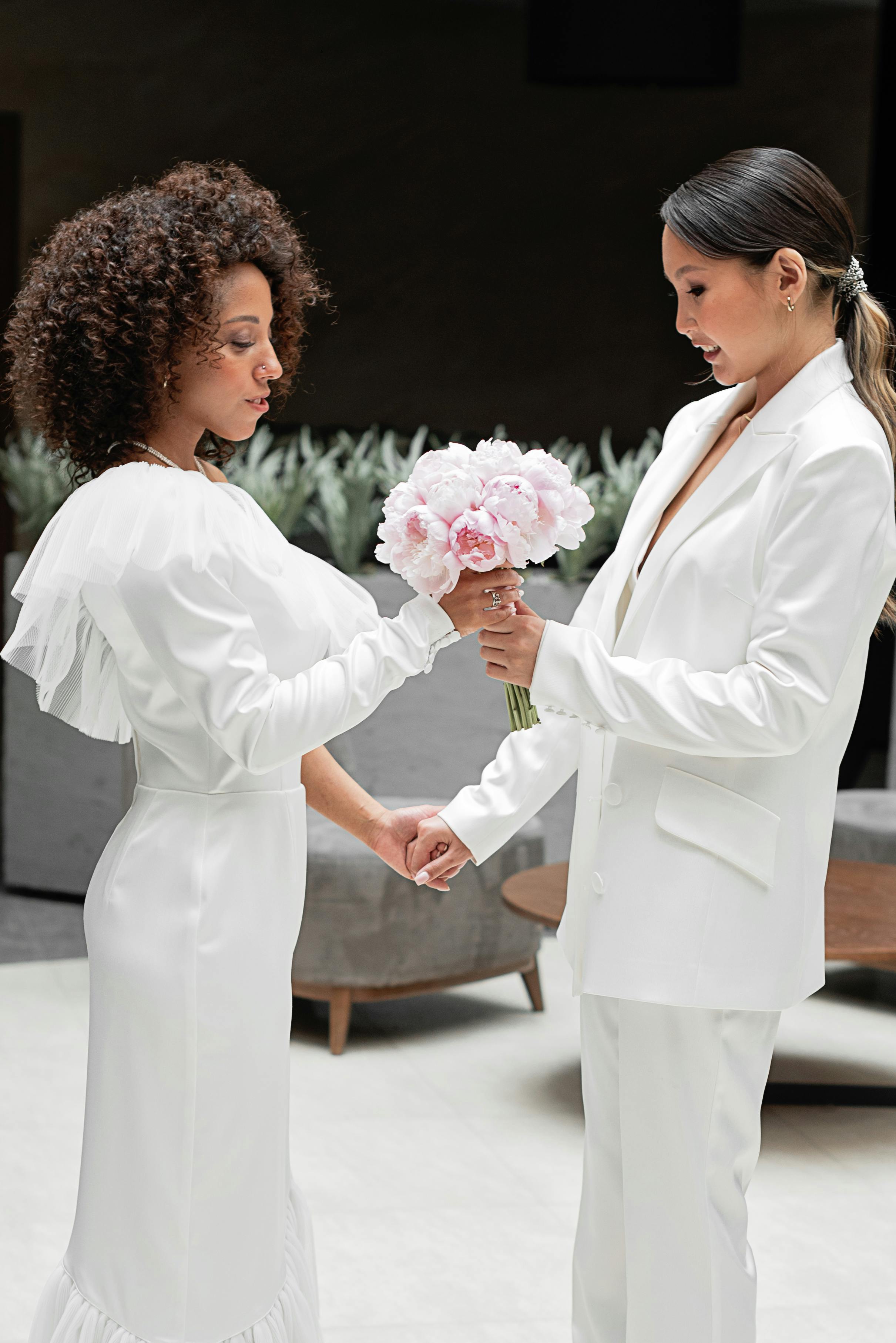 women holding each other s hands and looking at bouquet