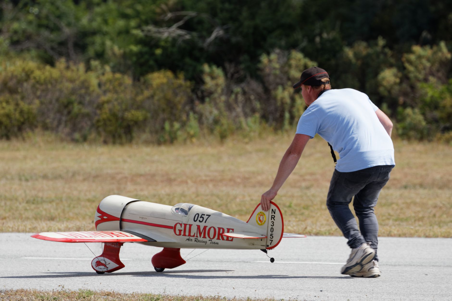 A man prepares to launch a model airplane on an outdoor runway, showcasing hobbyist passion.