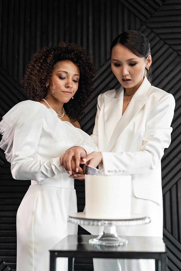 A Newlywed Couple Cutting A Wedding Cake Together