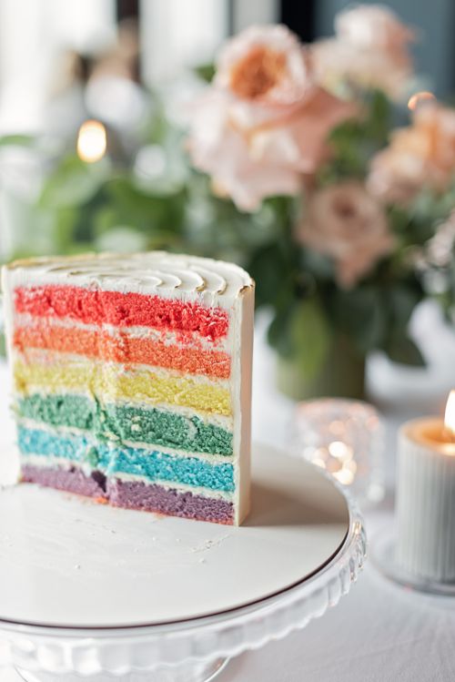 Free A vibrant rainbow layer cake on a white stand, perfect for celebrations. Stock Photo