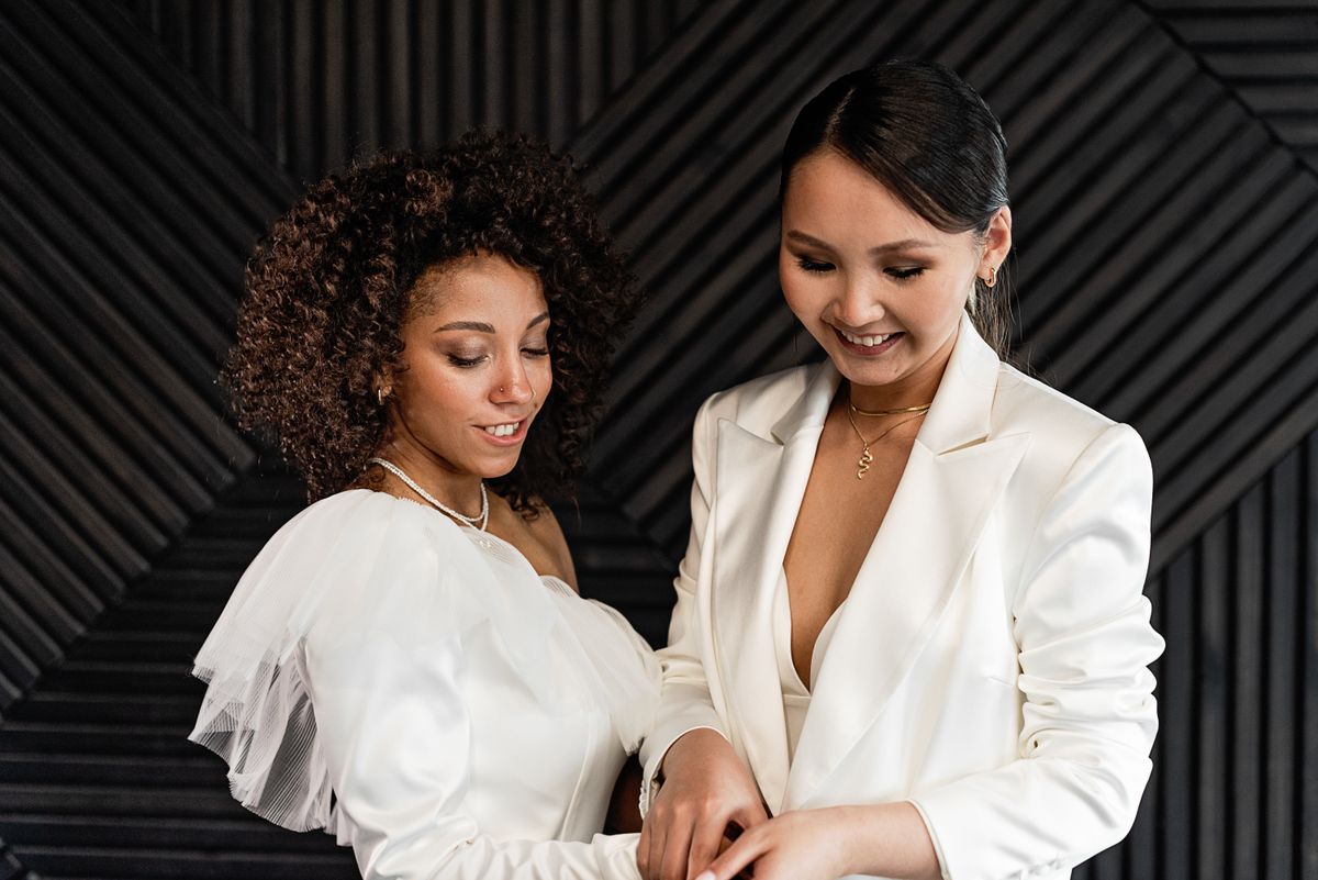 Two adult brides smiling together in a white dress and white suit