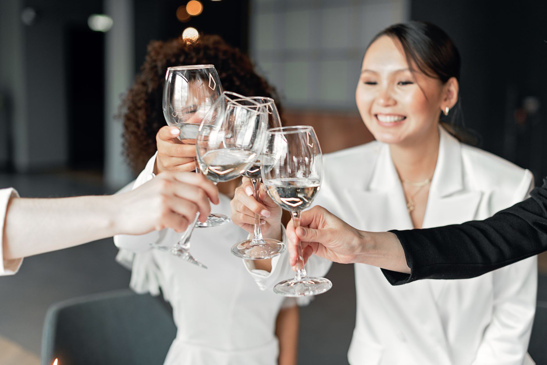 Newlyweds and guests raising glasses together in a warm indoor celebration