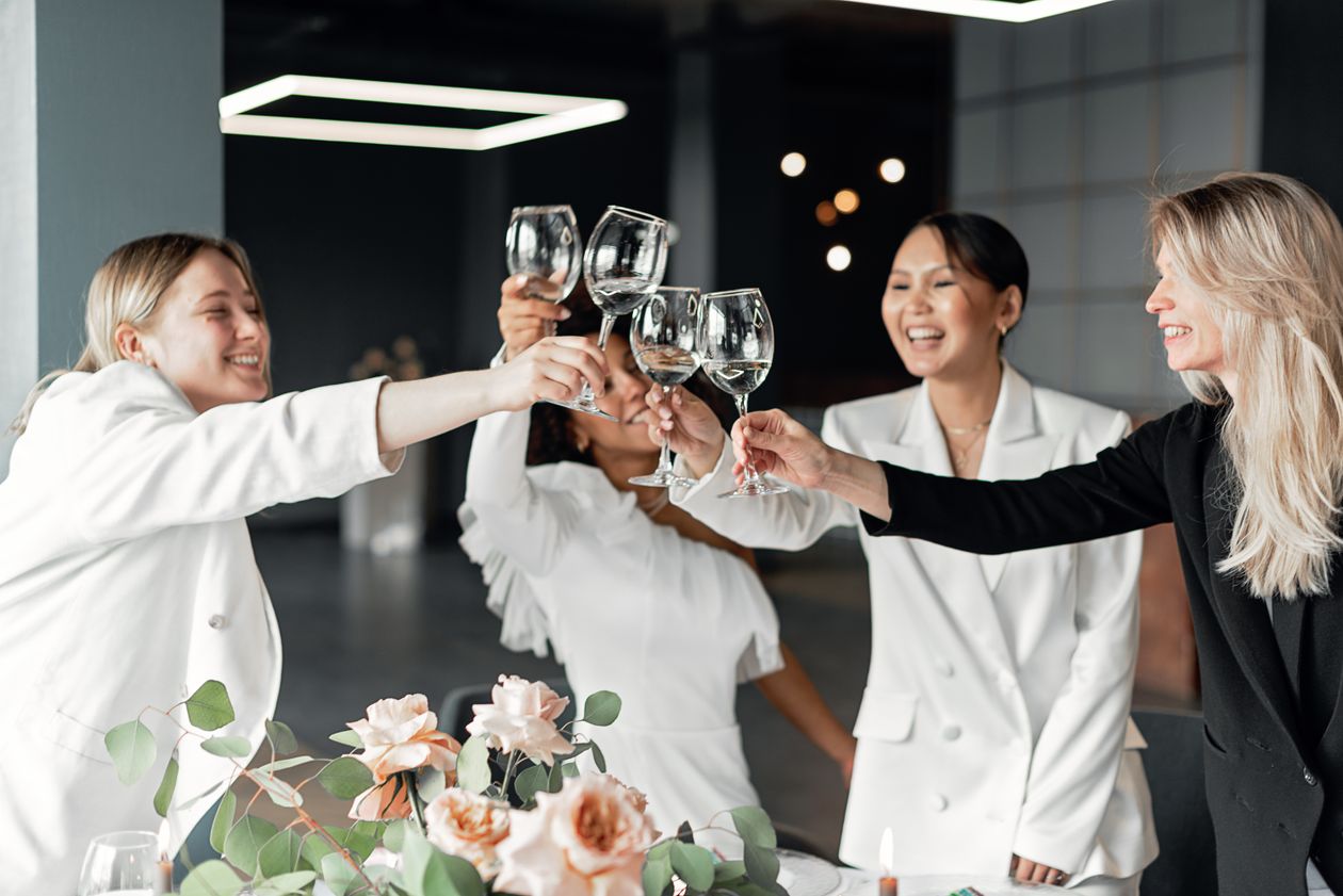 Friends toasting with wine glasses at a celebration with blush roses