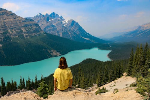 Free Person Sitting on Rocky Mountain Near Body of Water Stock Photo