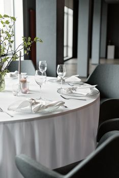 A beautifully set dining table with wine glasses and cutlery in a modern restaurant setting.