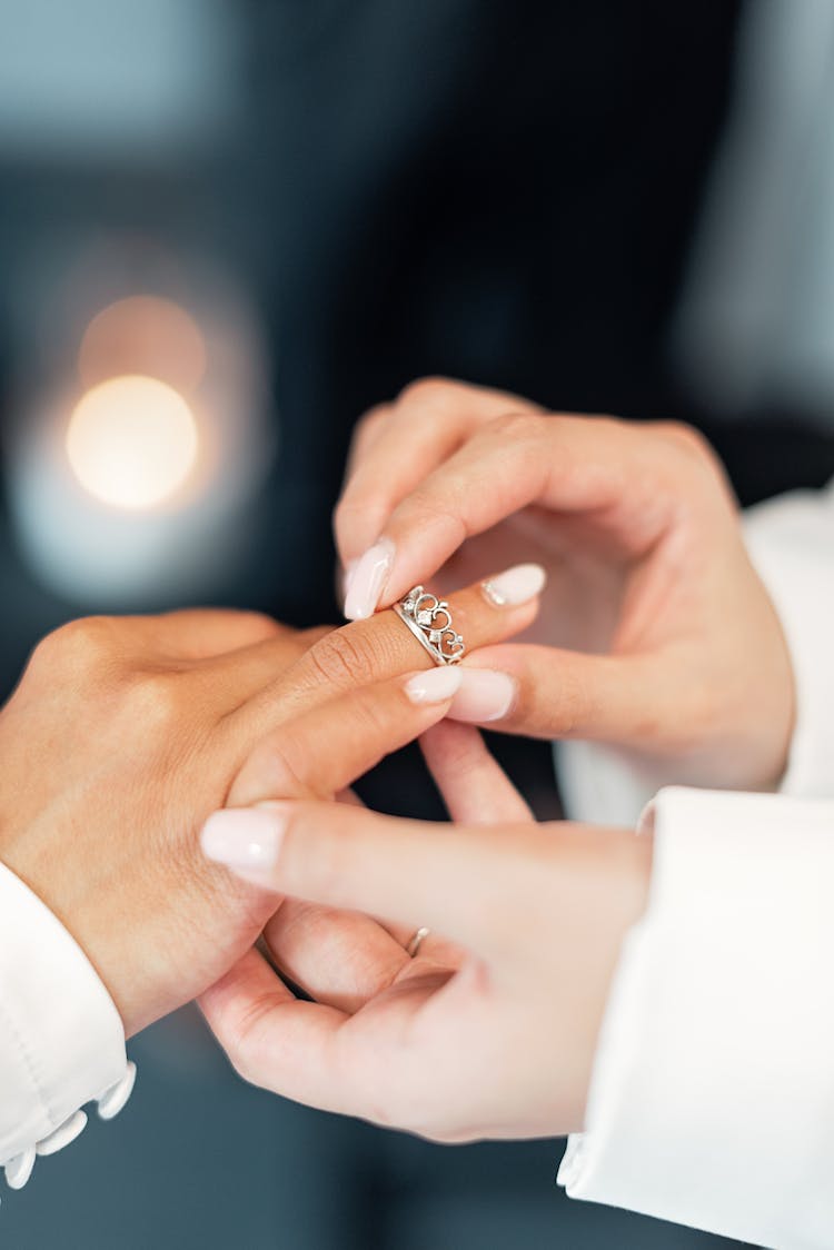 Person Putting On A Wedding Ring To Another Person