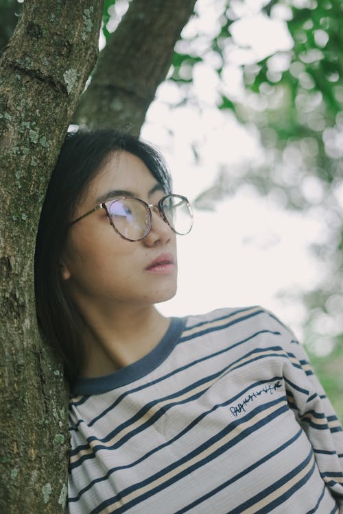 Young Woman Wearing Eyeglasses Leaning Against a Tree 