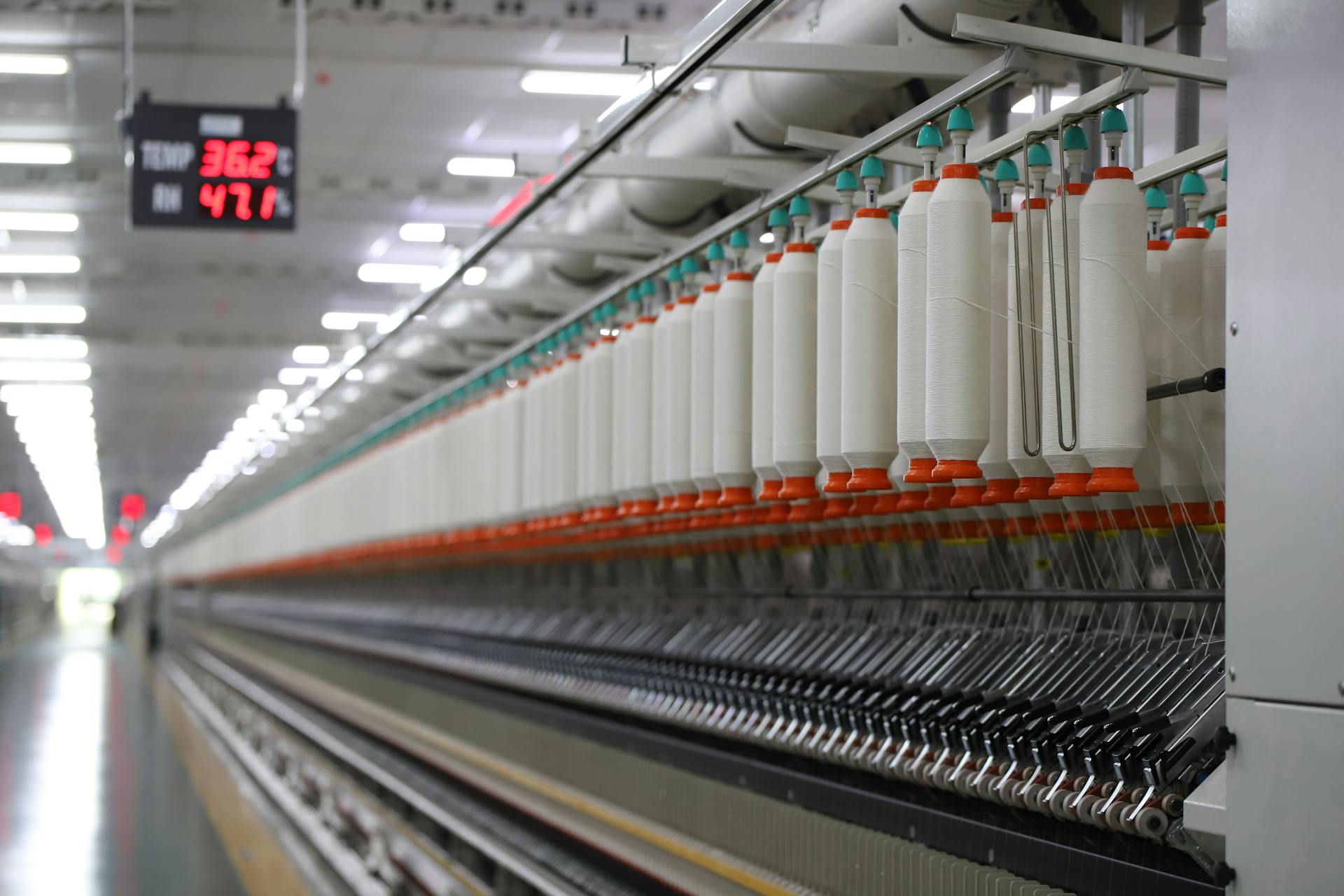 High-tech textile machinery with yarn spools in an Indian factory, demonstrating efficiency.