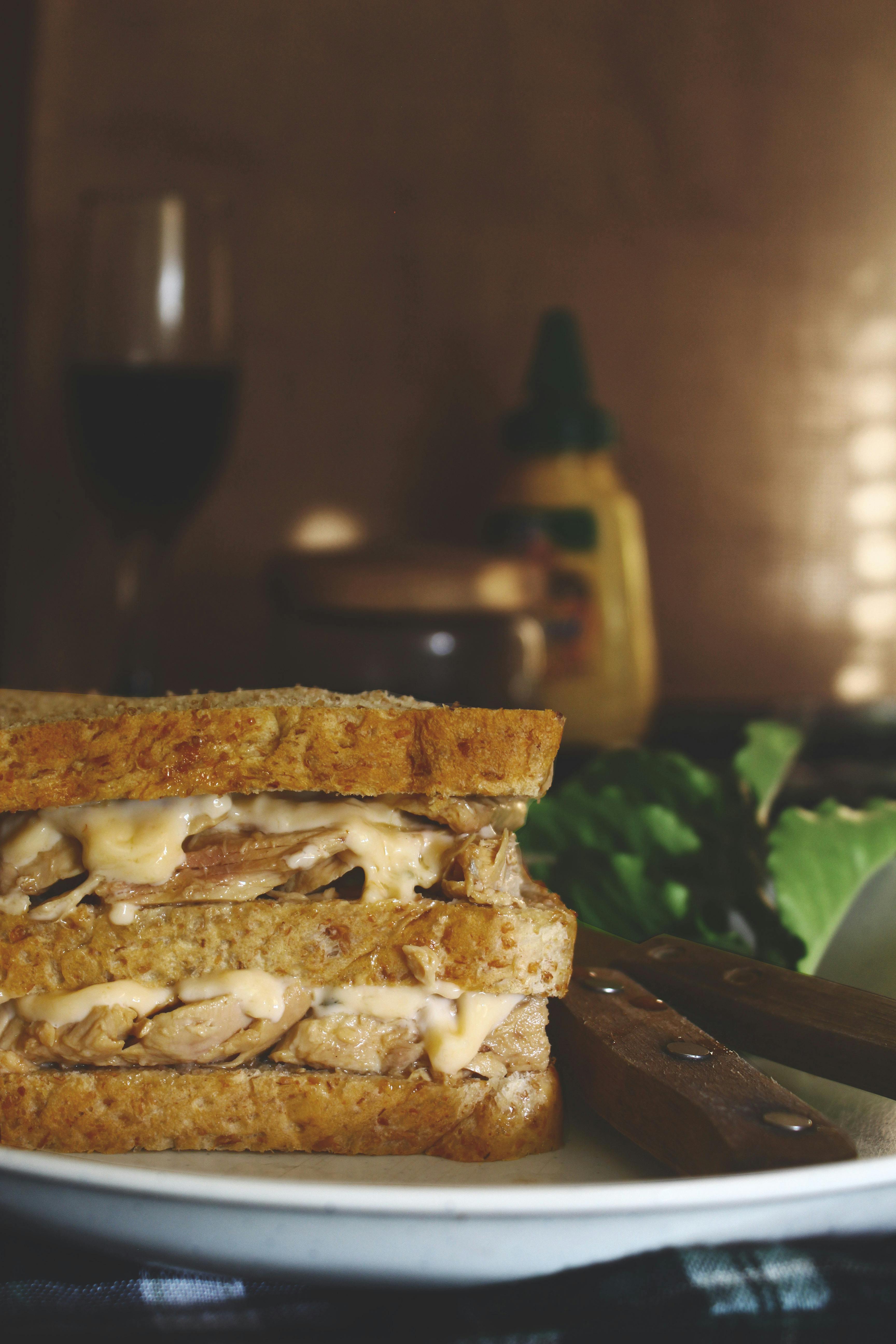 Delicious homemade grilled sandwich with cheese served on a wooden table beside a glass of wine.